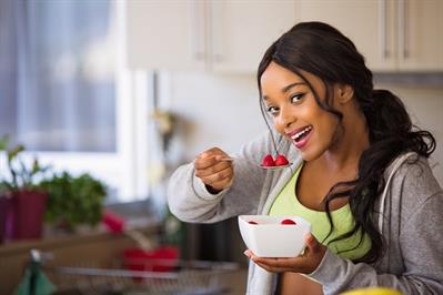 Breast Cancer and Diet: What's the Connection? - Young woman eating a bowl of Strawberries